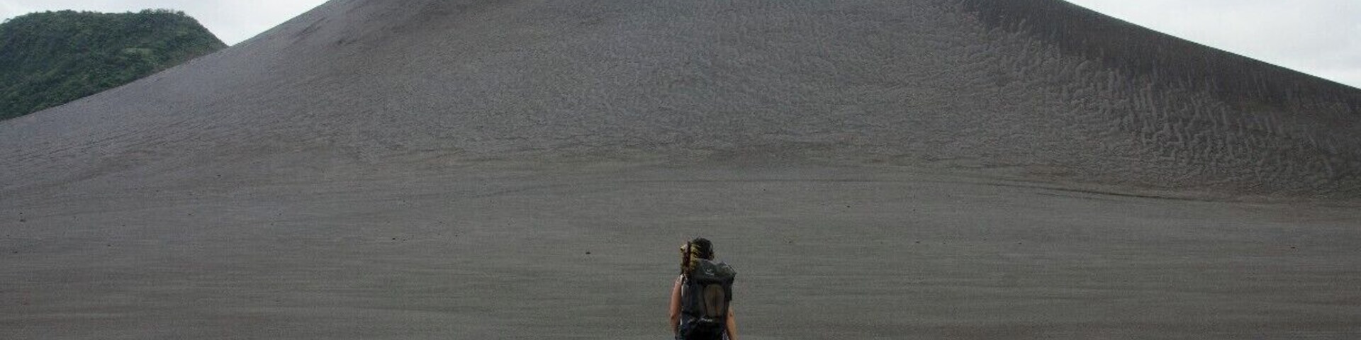 Una persona caminando hacia una colina grande y cónica.