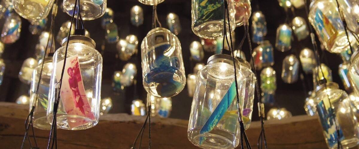 A collection of hanging glass jars with colorful contents.