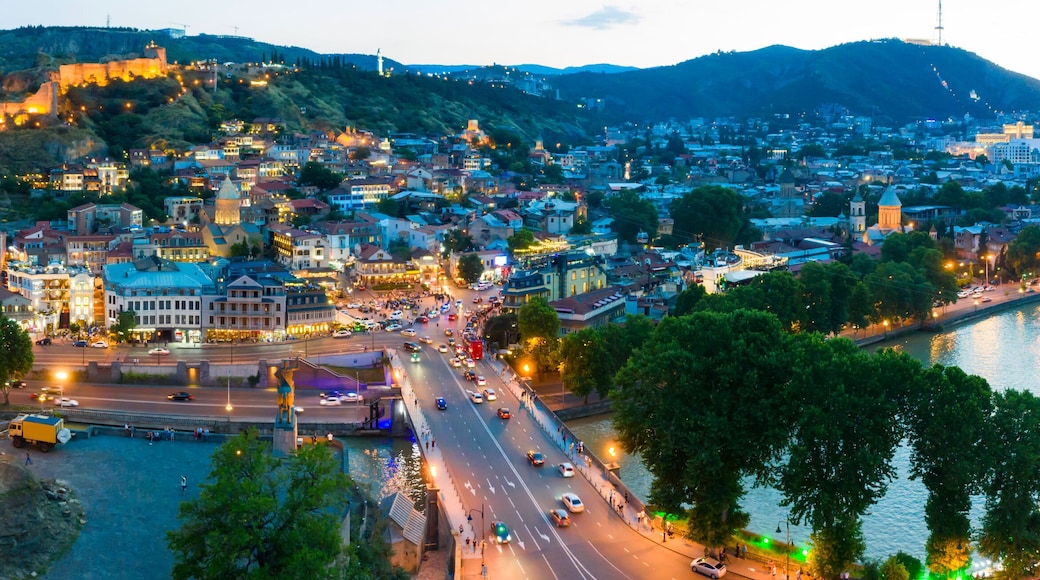 The evening panorama of the old town in the old district of Avlabari, Holy Trinity Cathedral and Rike Park, the Kura river reflects the evening city lights in Tbilisi, Georgia.