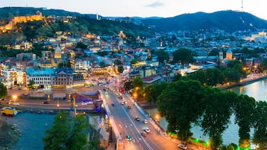 The evening panorama of the old town in the old district of Avlabari, Holy Trinity Cathedral and Rike Park, the Kura river reflects the evening city lights in Tbilisi, Georgia.