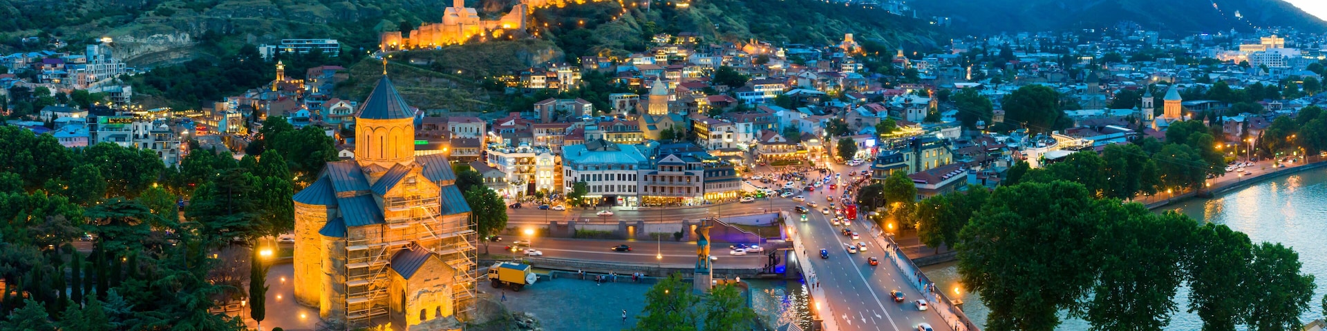 The evening panorama of the old town in the old district of Avlabari, Holy Trinity Cathedral and Rike Park, the Kura river reflects the evening city lights in Tbilisi, Georgia.
