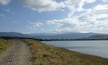 A gravel path beside a lake with mountains in the background.
