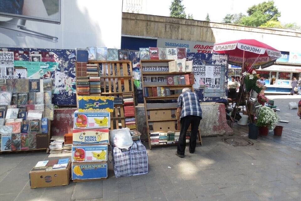 A street market with various items for sale, including books and boxes.
