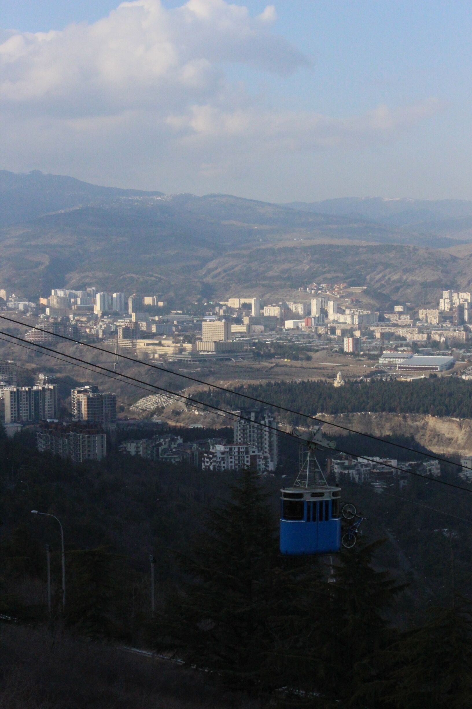 Newly re-opened aerial tram. View from the city of Tbilisi.

The Georgian capital of Tbilisi used to be home to an intricate system of aerial trams, that whisked people from lower elevations to the various hilltops around the city.

Most of these trams fell into disrepair following the collapse of the Soviet Union. One of these old tram stations recently re-opened. This tram connects Vake Park with the small Turtle Lake, which is located on a hillside above. 

You can even attach your bicycles to the tram (as is visible in this picture). 