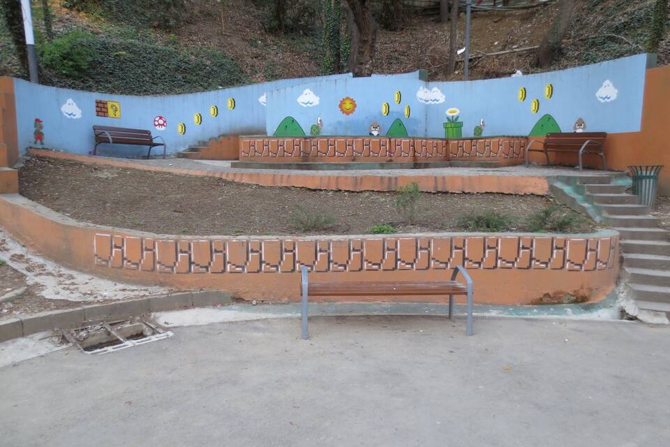 Un parque con un mural, bancos y una escalera.