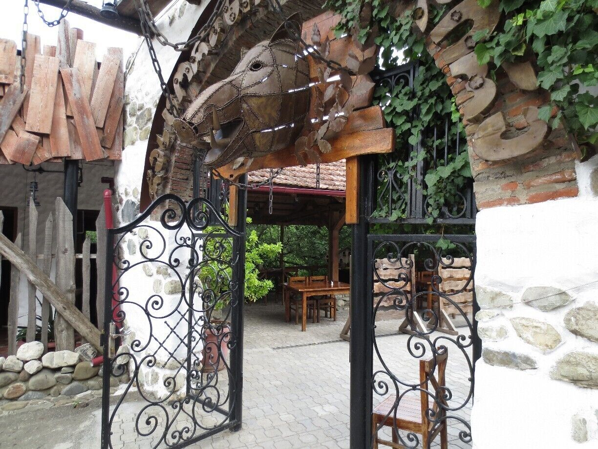 A rustic outdoor seating area with a wrought iron gate, wooden furniture, and a stone wall.