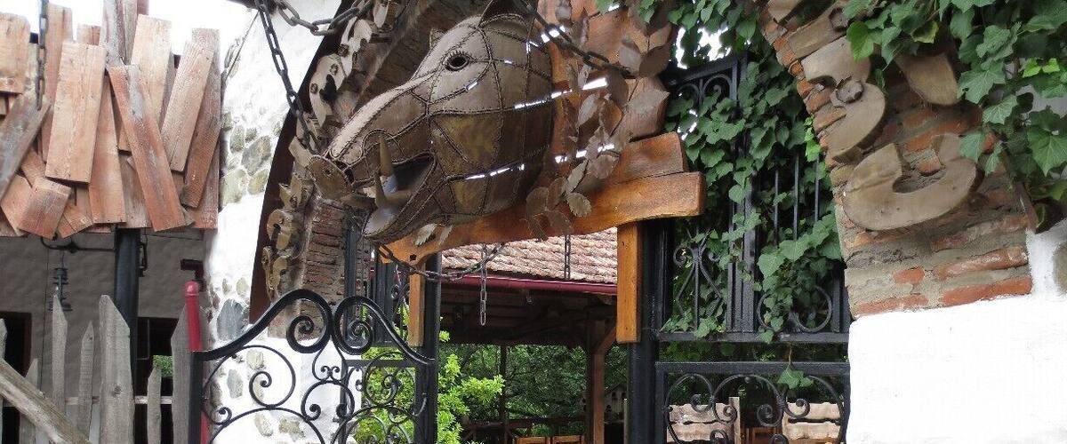 A rustic outdoor seating area with a wrought iron gate, wooden furniture, and a stone wall.