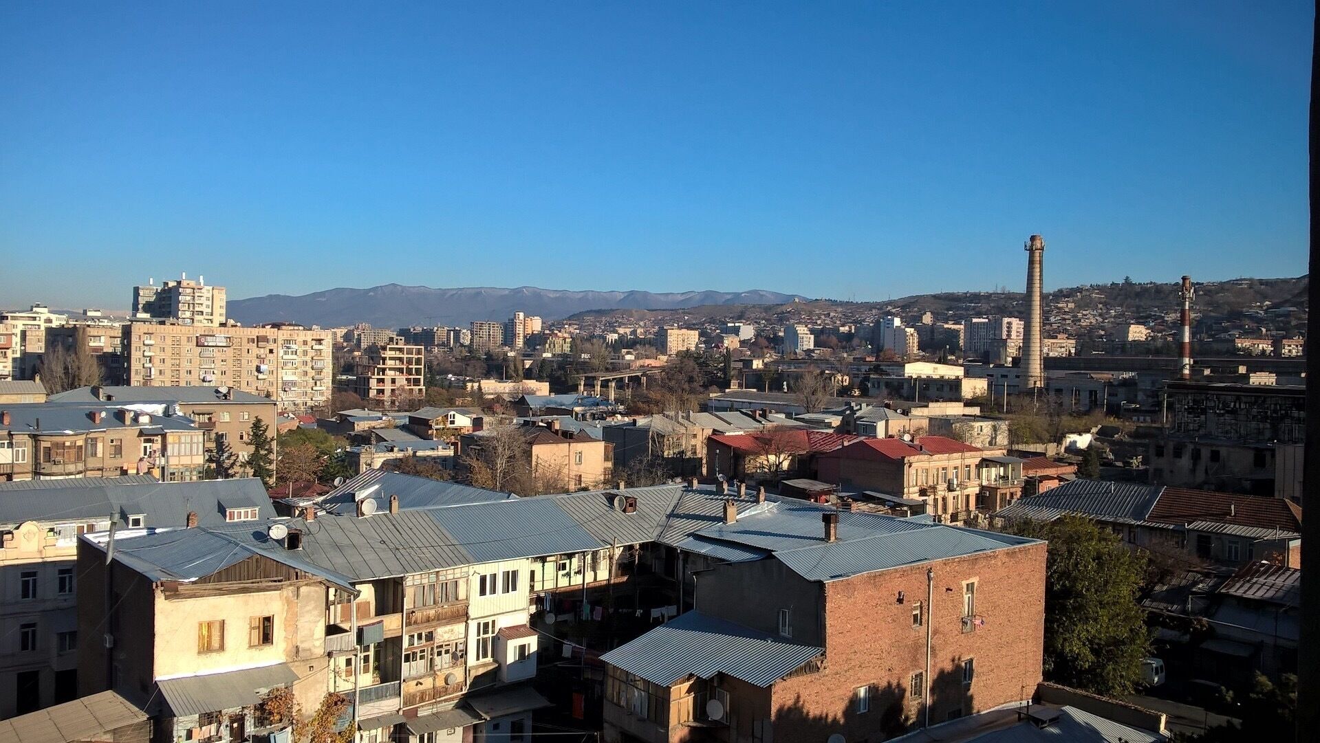 View from the city of Tbilisi on a crisp and cool November morning. A light dusting of snow is visible at the top top of the hills rising above the northern portion of the city. 
