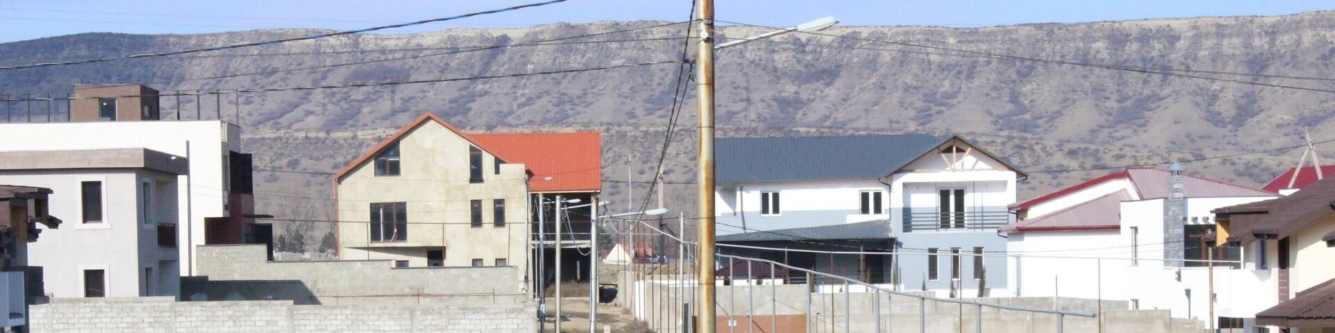 Man in a red shirt, squatting in an alleyway.
View from a new housing development in the city of Tbilisi.