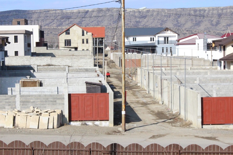 Man in a red shirt, squatting in an alleyway.
View from a new housing development in the city of Tbilisi.