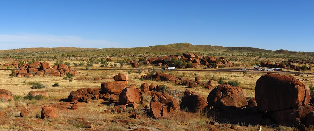 A desert landscape with large red rock formations and distant hills.