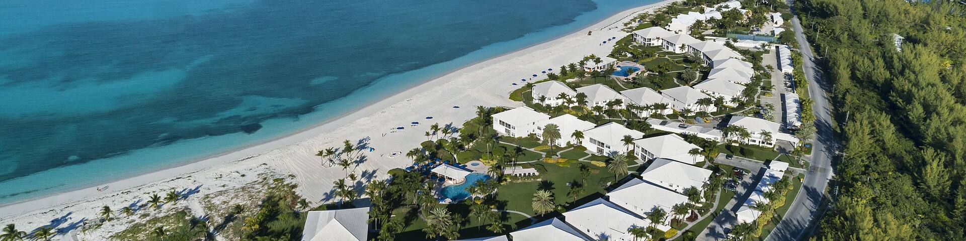A coastal resort with a beach, clear blue waters, and lush greenery.