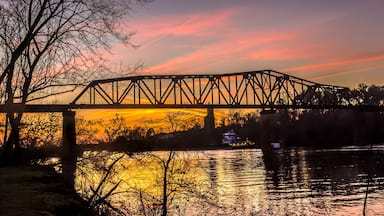 Un puente de acero sobre un río al atardecer, con el reflejo del cielo.