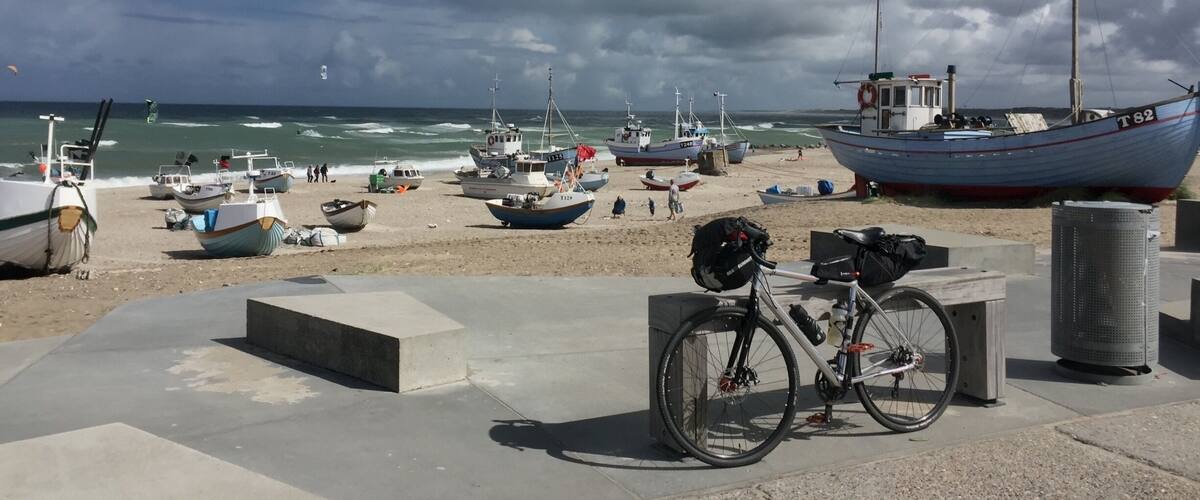 A beach with several boats, a bicycle, and a lifebuoy.