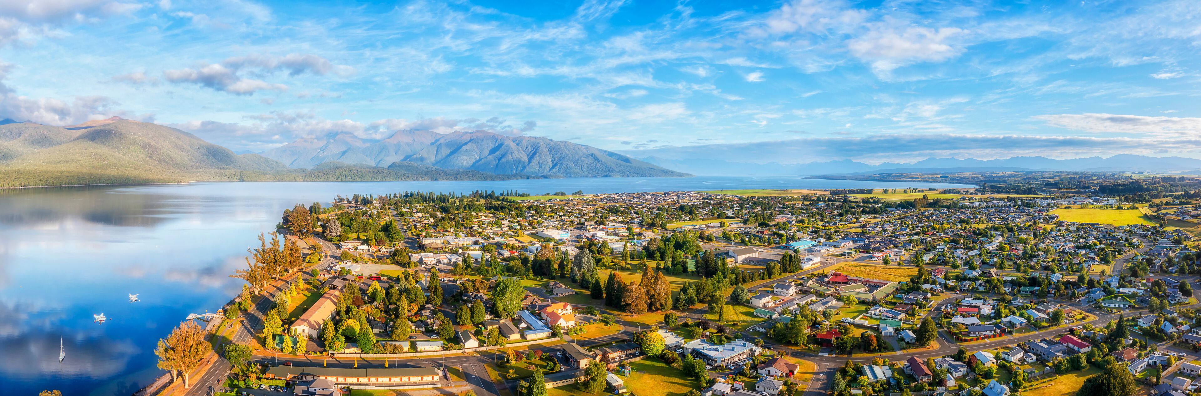 A coastal town with a lake, mountains, and residential areas.