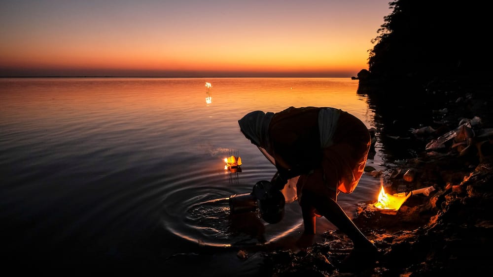Tezpur, India - November 2020: A woman making an offering with candles on the Brahmaputra River to celebrate Diwali on November 14, 2020 in Tezpur, Assam, India.