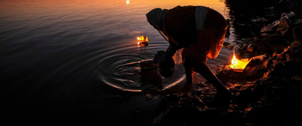Tezpur, India - November 2020: A woman making an offering with candles on the Brahmaputra River to celebrate Diwali on November 14, 2020 in Tezpur, Assam, India.