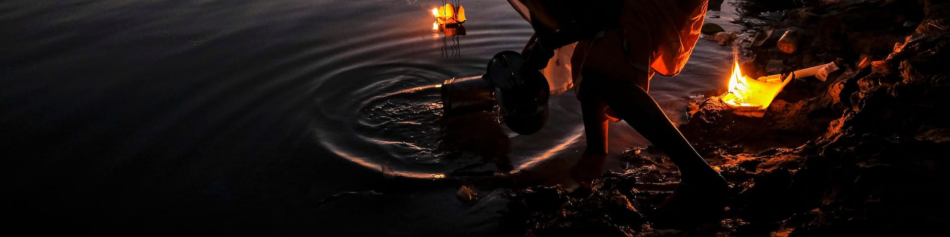 Tezpur, India - November 2020: A woman making an offering with candles on the Brahmaputra River to celebrate Diwali on November 14, 2020 in Tezpur, Assam, India.