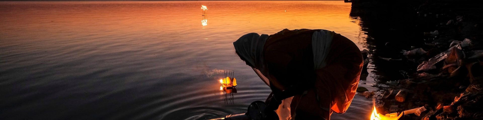 Tezpur, India - November 2020: A woman making an offering with candles on the Brahmaputra River to celebrate Diwali on November 14, 2020 in Tezpur, Assam, India.