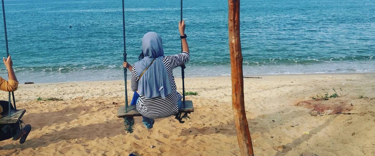 A person on a swing overlooking the sea.