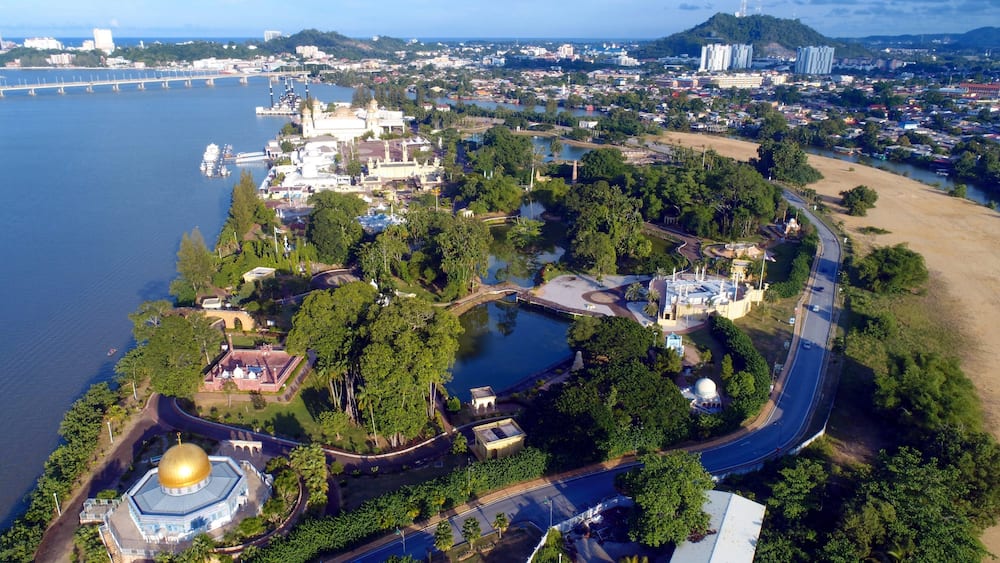 An aerial view of a coastal city with a prominent church, a bridge, and a river.