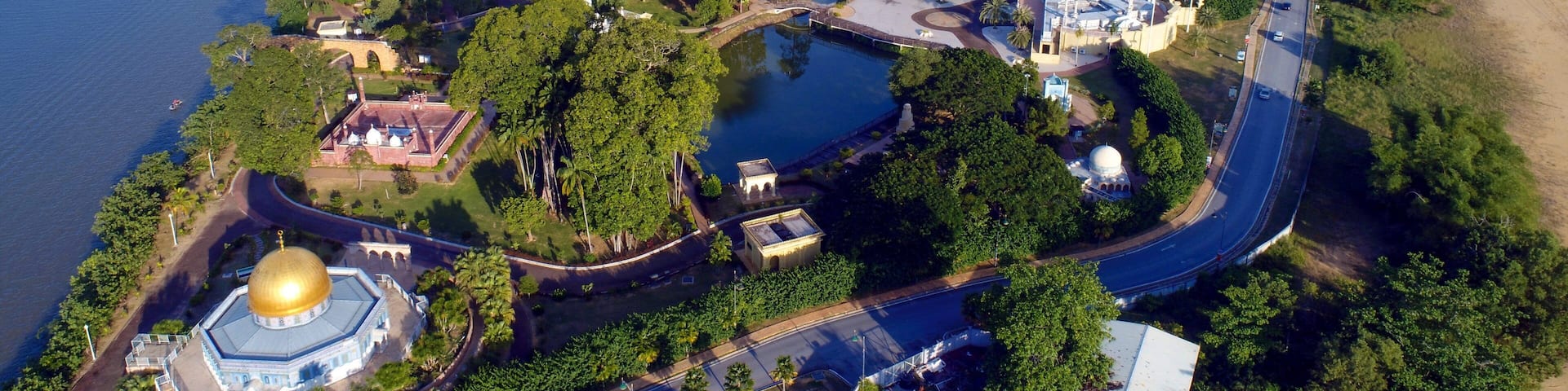 An aerial view of a coastal city with a prominent church, a bridge, and a river.