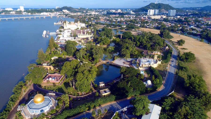 An aerial view of a coastal city with a prominent church, a bridge, and a river.