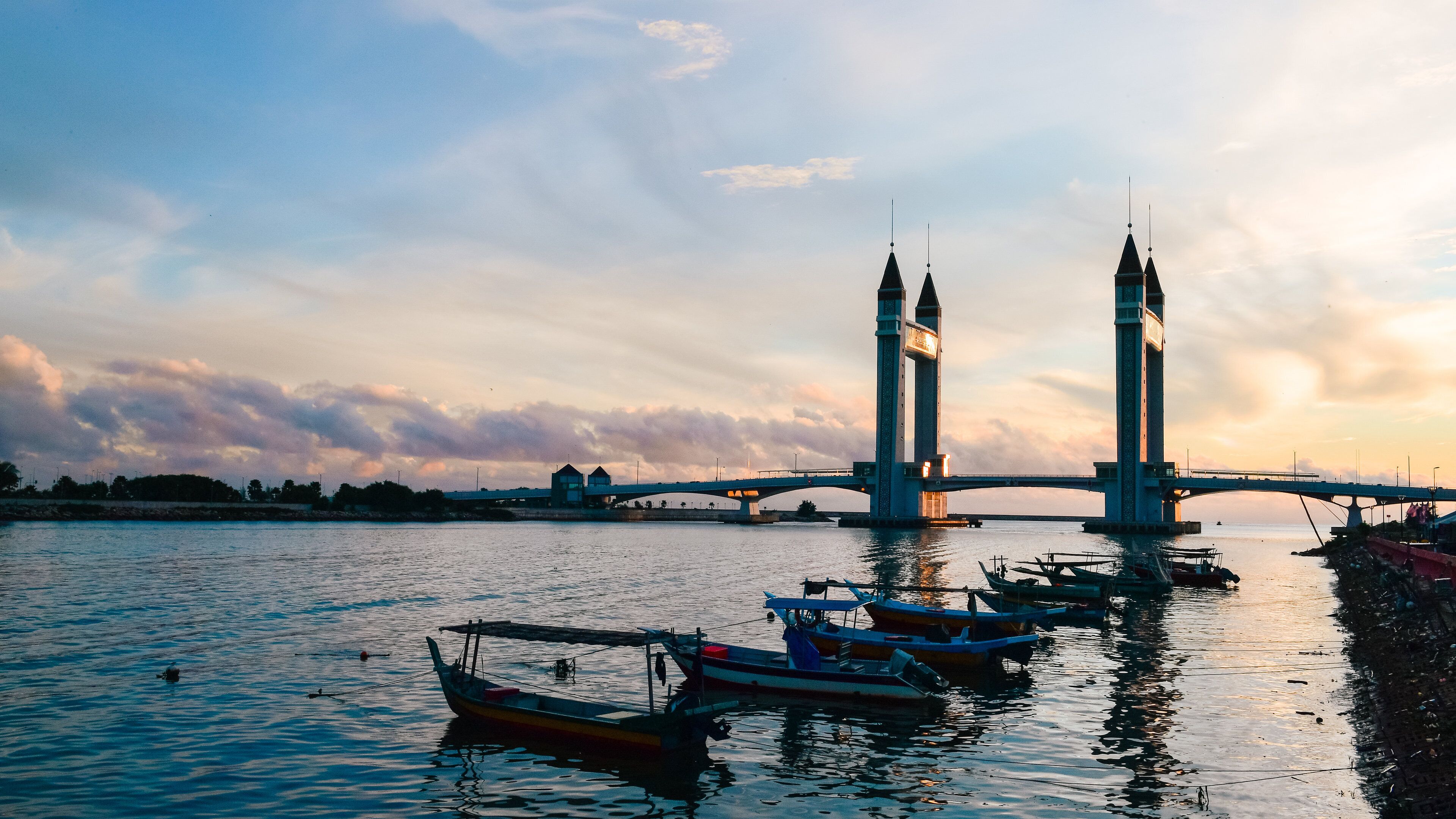 A bridge with two towers over a body of water with boats.