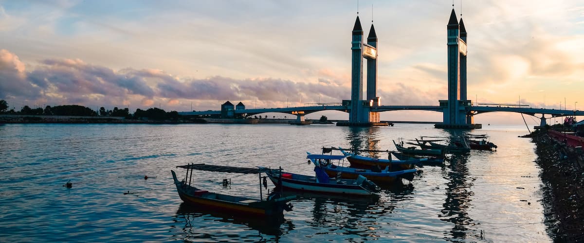 A bridge with two towers over a body of water with boats.