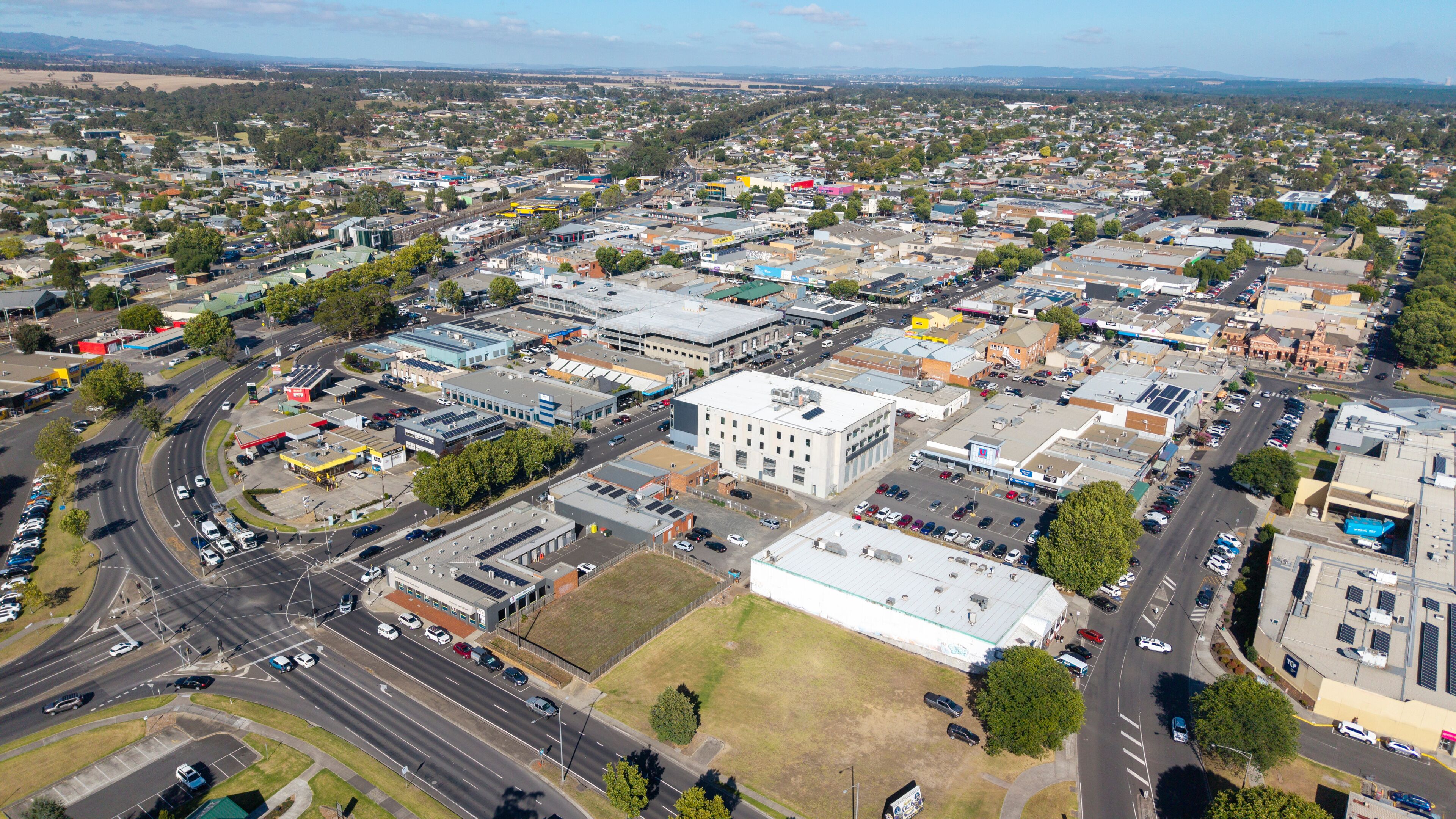 A densely populated urban area with a mix of commercial and residential buildings, a central roundabout, and a large industrial facility.