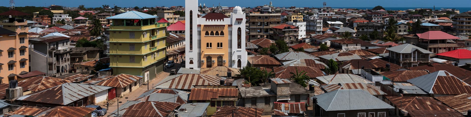 A coastal cityscape with a prominent white church tower, colorful buildings, and a mix of residential and commercial structures.