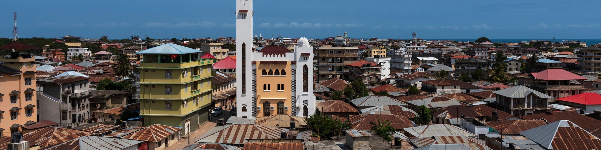 A coastal cityscape with a prominent white church tower, colorful buildings, and a mix of residential and commercial structures.