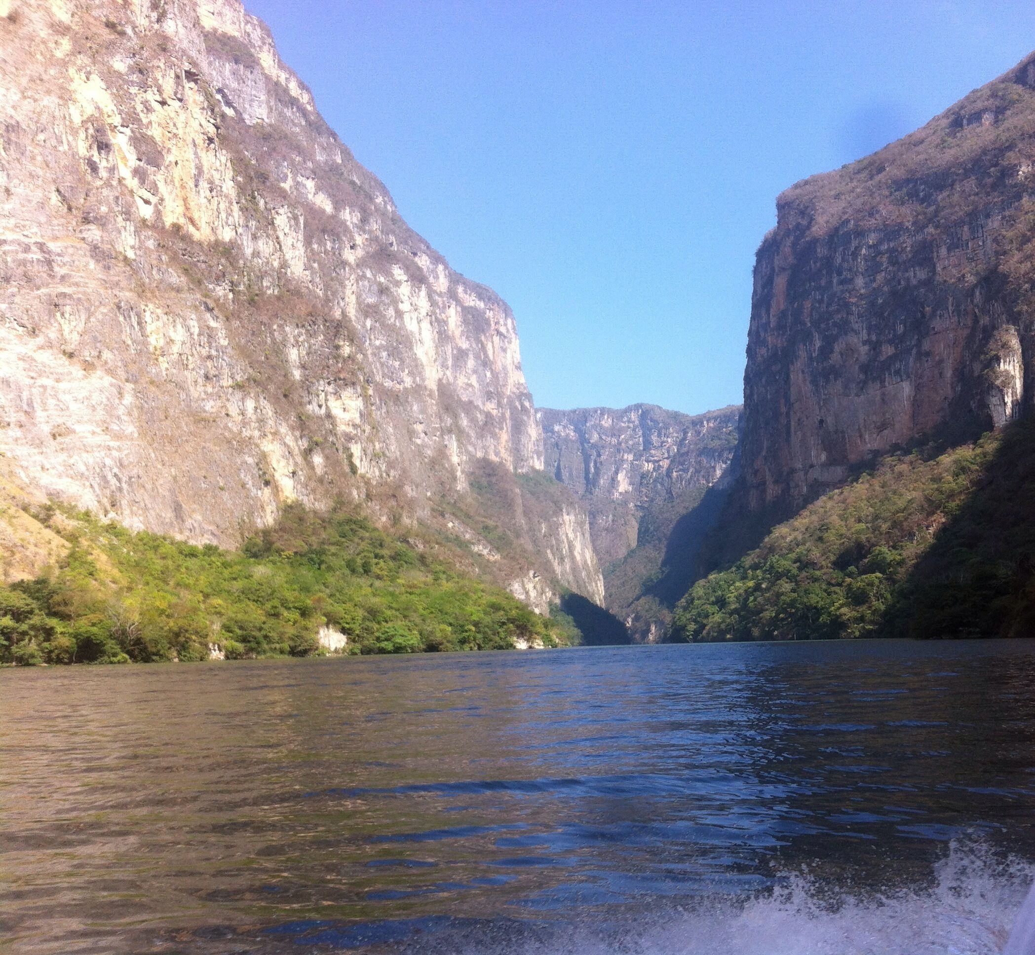 A river canyon with steep cliffs and lush greenery along the riverbanks.