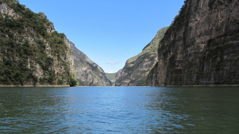 A canyon with steep cliffs and a calm river.