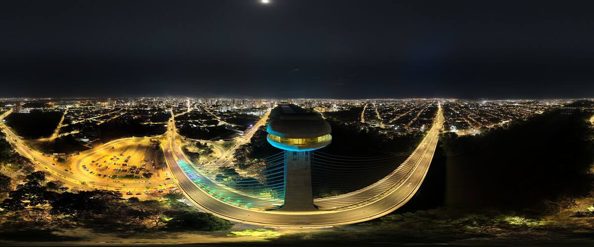 A cityscape at night with a prominent tower and a curved road.