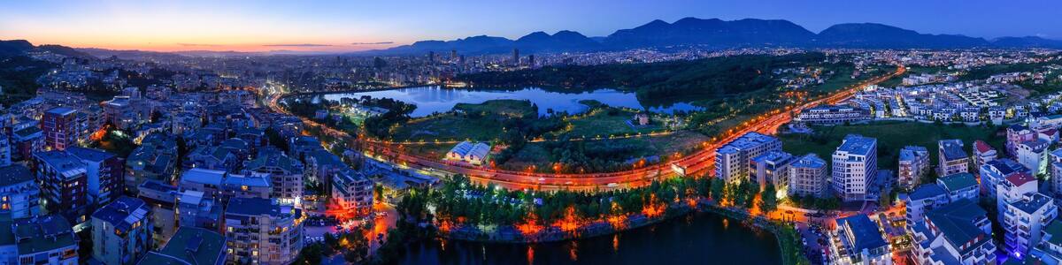 Panoramic aerial image of the city of Tirana from the outer ring road showing the artificial lake after the Sunset.