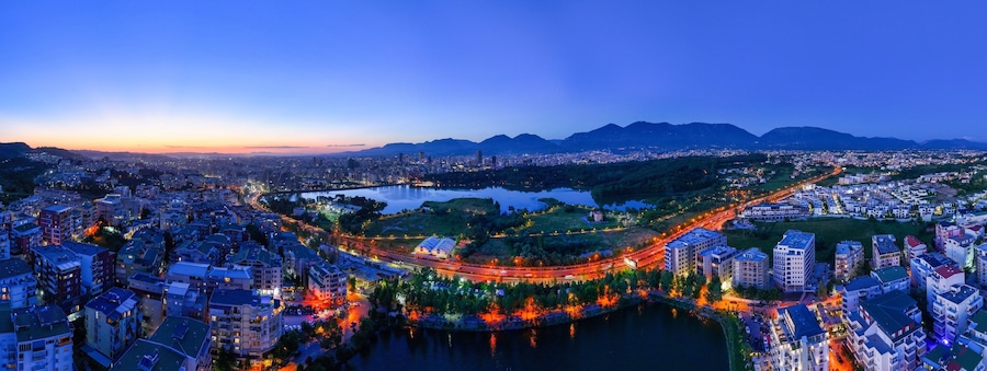 Panoramic aerial image of the city of Tirana from the outer ring road showing the artificial lake after the Sunset.