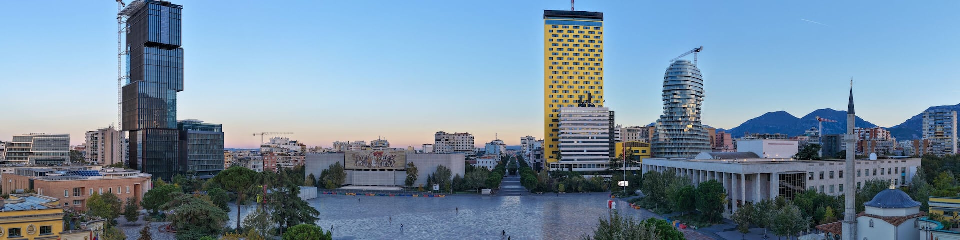 Aerial panorama of Skanderbeg Square at Dawn surrounded by modern towers and city landmarks.