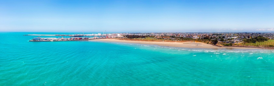 Una ciudad costera con playa, puerto y zona industrial.