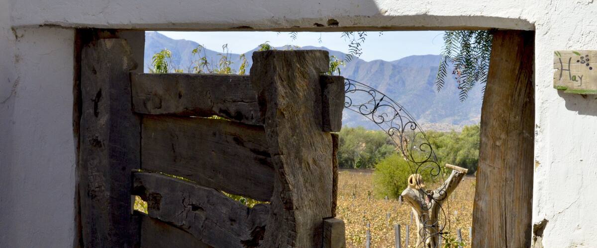 Une porte en bois rustique, sur laquelle on peut lire l’inscription « Foin », dans un cadre rural avec des montagnes en arrière-plan.
