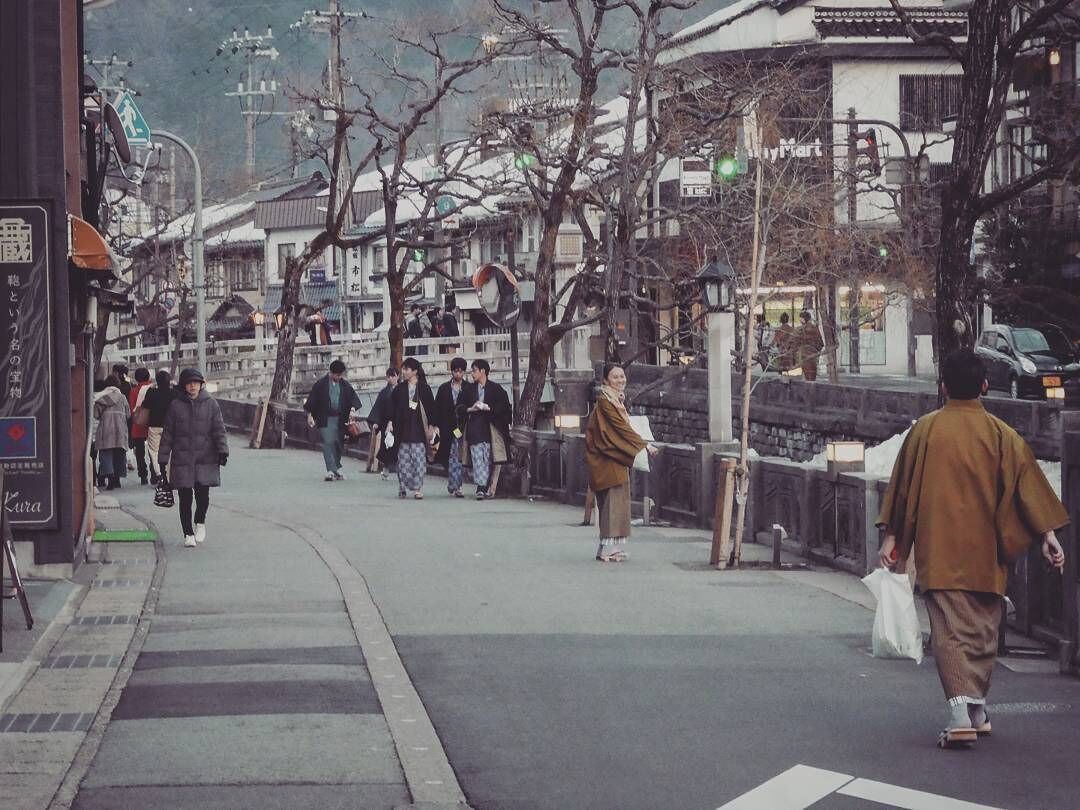 A busy urban street with pedestrians, traditional buildings, and a crosswalk.