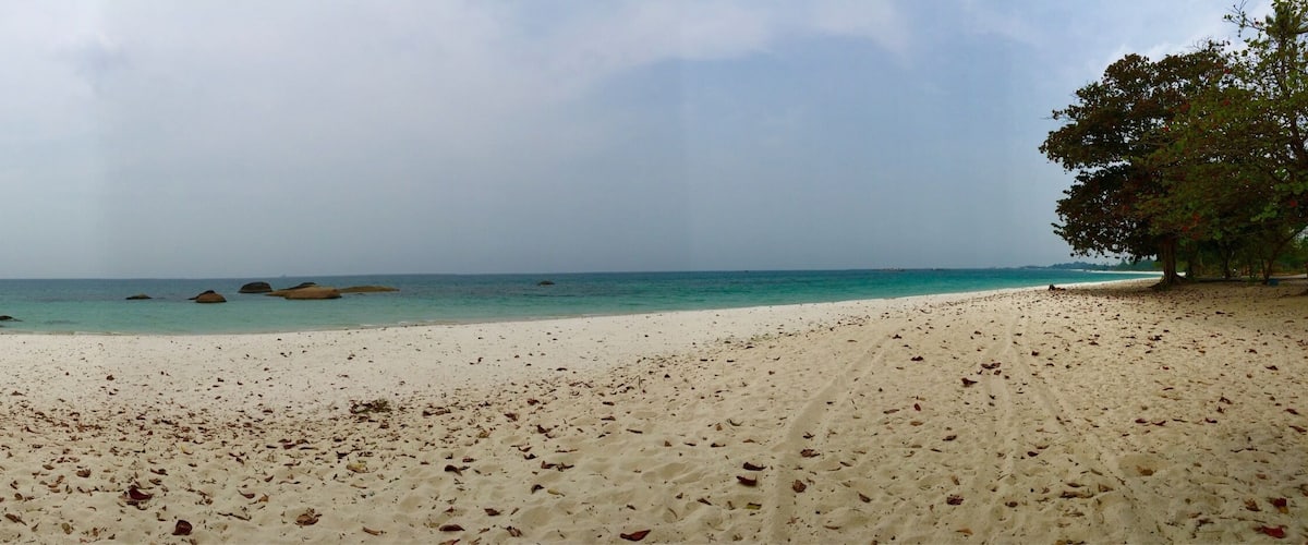 Una playa de arena blanca con rocas dispersas.