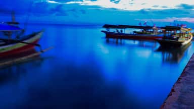 Long exposure shot of the ocean and a pier in a blue time with the old boats defocused. uploaded at Bandar Lampung. Indonesia in May 2019. Traveling concept