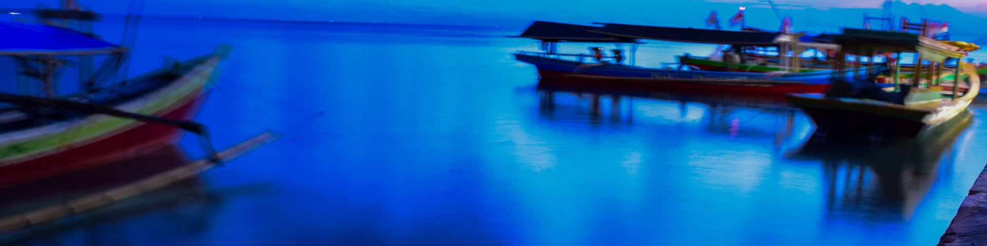 A calm body of water with boats docked along the shore.