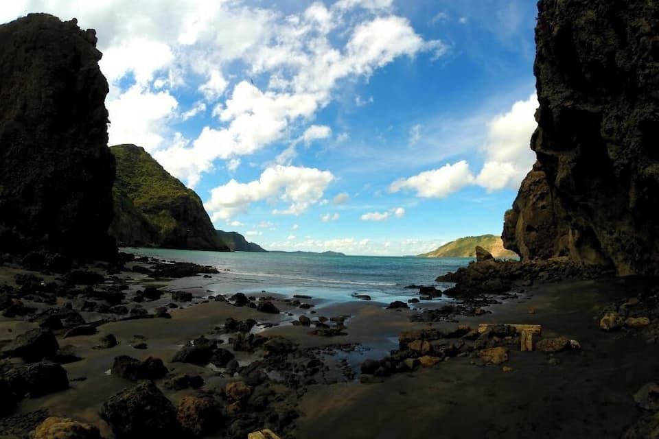 Ein felsiger Strand mit großen Steinen und blauem Himmel.