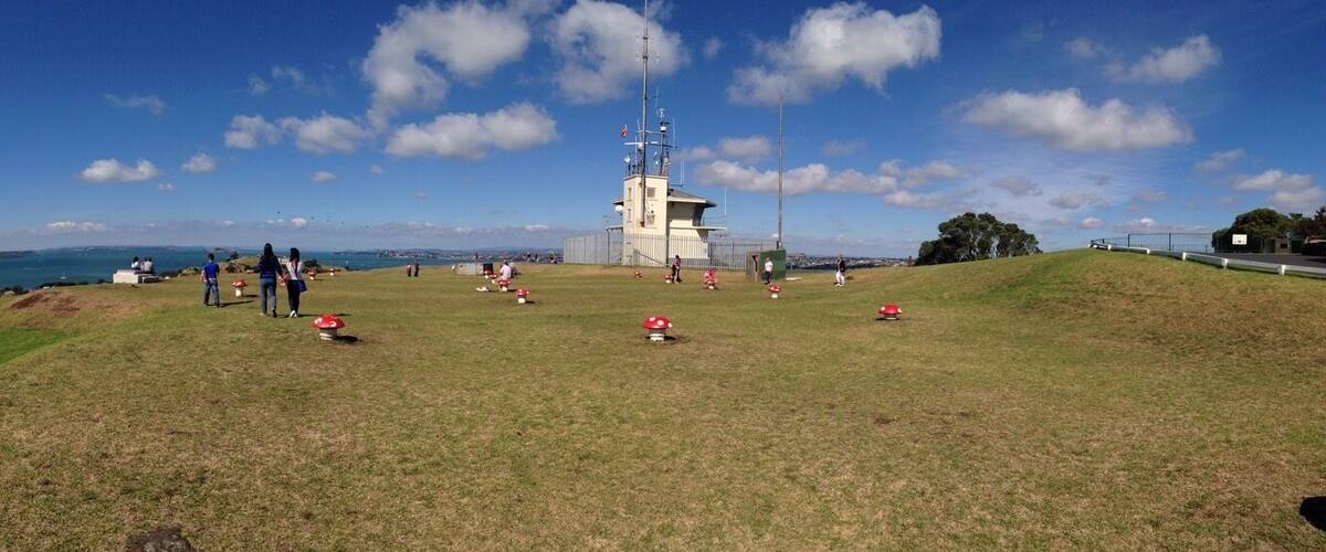 A grassy hill with a small tower and red mushroom decorations.