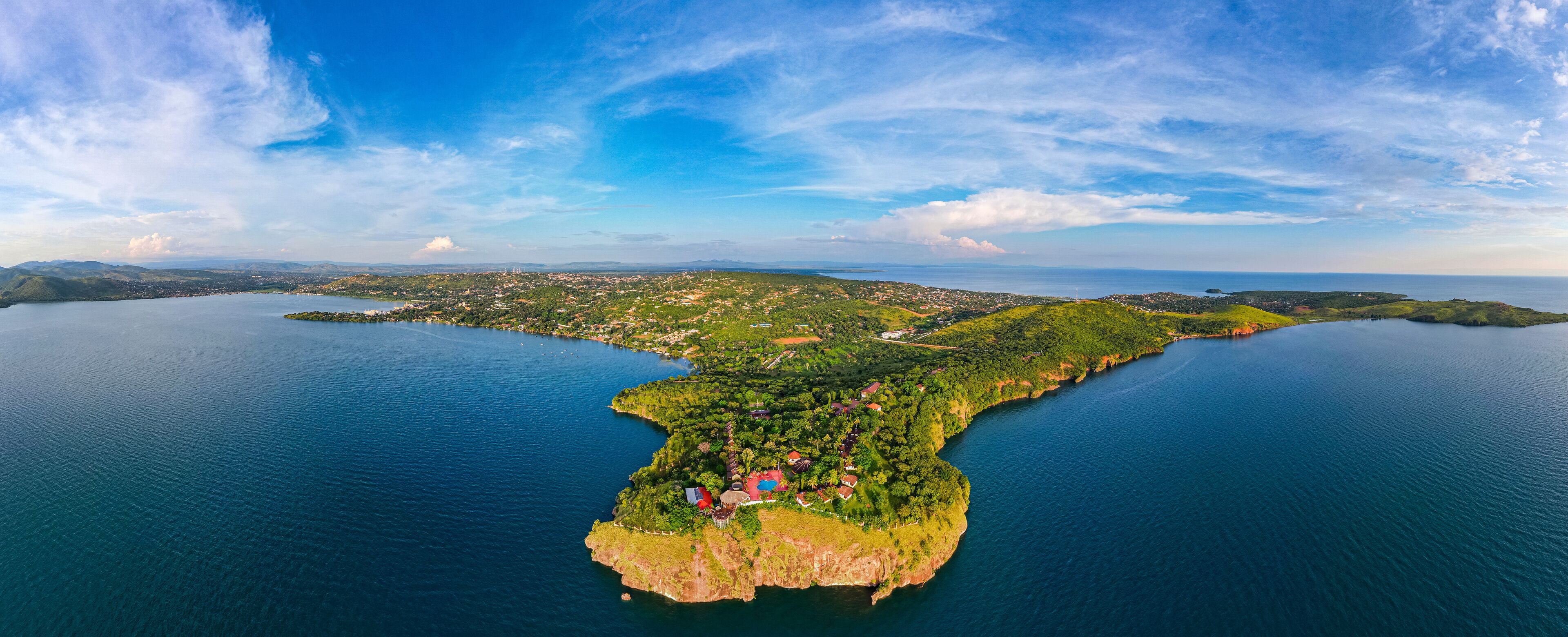 An aerial view of a coastal island with a clear blue sky, surrounded by water.