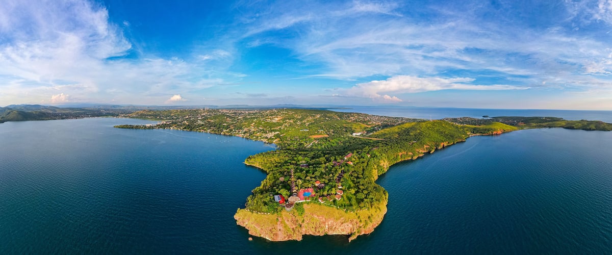 An aerial view of a coastal island with a clear blue sky, surrounded by water.