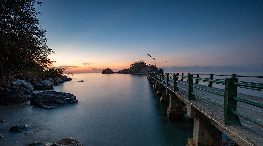 Sunset on a bridge connecting sulawesi main island and sabang tende island, tolitoli, central sulawesi, indonesia with visible rock and coral using long exposure