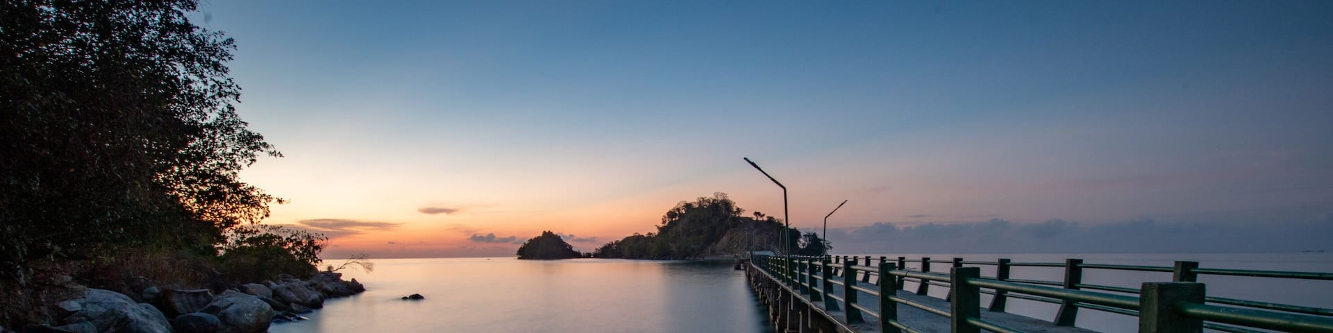 Sunset on a bridge connecting sulawesi main island and sabang tende island, tolitoli, central sulawesi, indonesia with visible rock and coral using long exposure